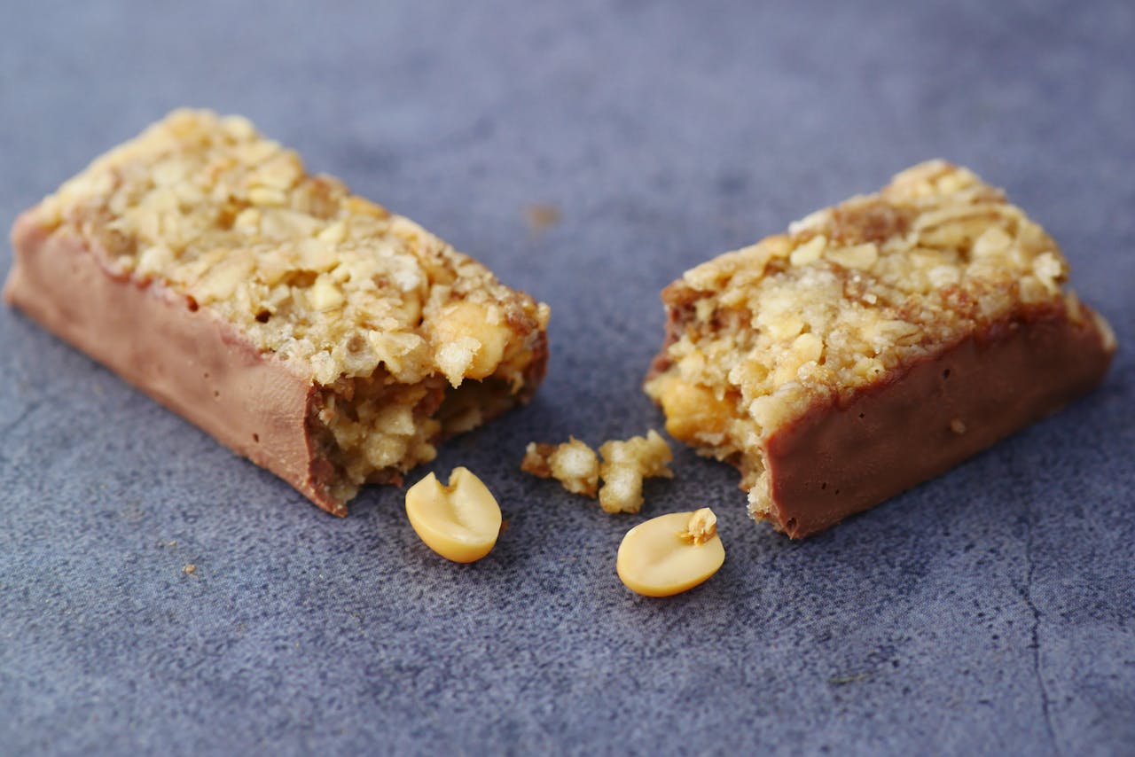 Close-up of a broken chocolate and nut energy bar on a gray surface.